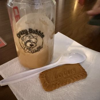Crazy Bubble Waffle - Affogato - A beverage in a Crazy Bubble Waffle branded can, accompanied by a cookie and a plastic spoon on a napkin, on a wooden table. - Desserts Near Me - Miami, Florida
