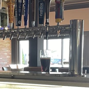Barrel House - Proper Guinness pour! - A pint of dark beer sits on a bar counter beneath multiple beer taps with various handles, inside a pub or bar setting. - American Near Me - Bloomington, Illinois