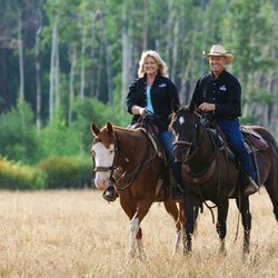 Rawah Ranch - Rawah Guest Ranch - Couple riding horseback through a grassy meadow
