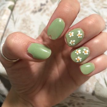 Nails Uncorked Amazon - chipped nails - A hand displays nails painted with light green polish, some with chipped areas, and floral designs on two nails. - Nail Salons Near Me - Eugene, Oregon