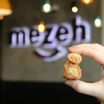 Mezeh - a hand holding a piece of food - Mediterranean Near Me - Lake Ridge, Virginia