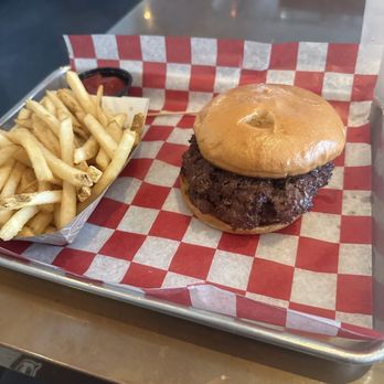Burger Daddy - Double burger and fries - A tray holds a burger with a fried chicken patty and a bun, accompanied by French fries and a small container of dipping sauce. - Burgers Near Me - Stuart, Florida