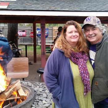 City Hall Saloon and Eatery - a man and woman standing in front of a fire pit - Bars Near Me - Enumclaw, Washington