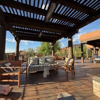 SkyFire - Open-air patio with wooden chairs, sofas, and tables under a pergola at SkyFire restaurant in Santa Fe, NM. - American Near Me - Santa Fe, New Mexico