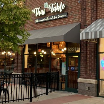Thai Table - Outside - The image shows the storefront of Thai Table, a Thai and Lao cuisine restaurant, with outdoor seating and illuminated signage. - Thai Near Me - Frederick, Maryland
