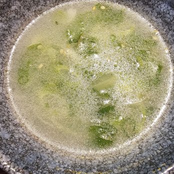 Y Space BBQ - Fragrant Beef Bone Soup - A ceramic bowl filled with beef bone soup containing green vegetables and clear broth. The bowl has a textured, dark exterior and is placed on a surface with a reddish hue. The image includes a timestamp indicating it was taken on June 4, 2025, at 8:58 PM. - Barbeque Near Me - Flushing, New York
