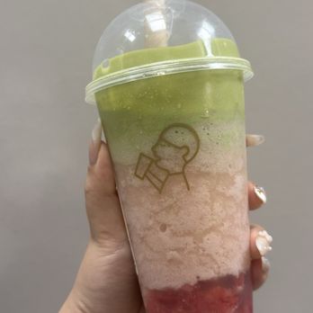 Heytea - A multi-layered beverage in a clear plastic cup with a dome lid and straw, featuring green, pink, and red layers, held by a person with decorated nails. - Bubble Tea Near Me - Toronto, Ontario