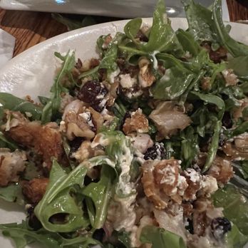 Lost Dog Pub - Arugula salad with coconut shrimp - A salad featuring arugula, coconut shrimp, walnuts, dried cranberries, and a creamy dressing, served on a white plate. - American Near Me - South Dennis, Massachusetts