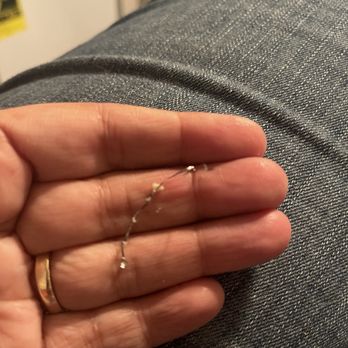 Lucky Wok - Wire found in my egg drop soup - A person holds a thin, silver chain with small beads or stones, resting on their fingers, with a gray fabric background. - Chinese Near Me - Albuquerque, New Mexico