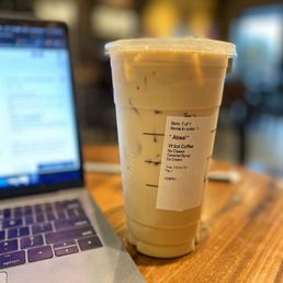 a cup of iced coffee next to a laptop