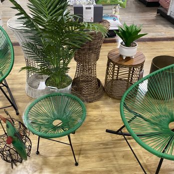 HomeGoods - Arrangement of green wire chairs, wicker tables, and potted plants on a wooden floor in a retail store setting. - Home Decor Near Me - Chicago, Illinois