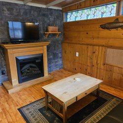 Robin Hood Village Resort - Cabin 5 living area with futon, coffee table, fireplace, and small tv.
