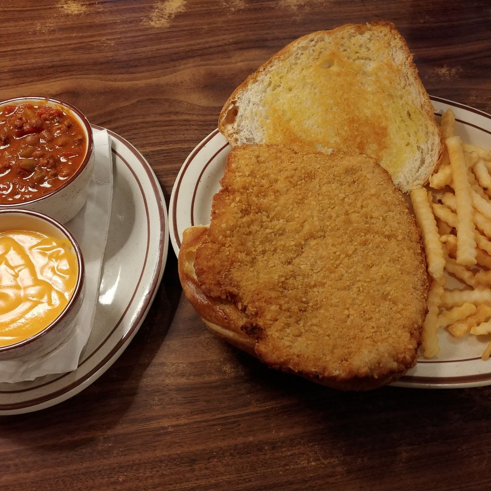 Large breaded tenderloin with fries and a side of chili and cheese sauce.