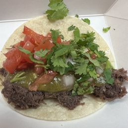 Barbacoa taco - i added the toppings from their bar - A taco filled with shredded beef, topped with diced tomatoes, cilantro, and green sauce, served on a soft tortilla.