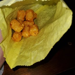 a person holding a paper bag filled with tater tots a person holding a paper bag filled with tater tots