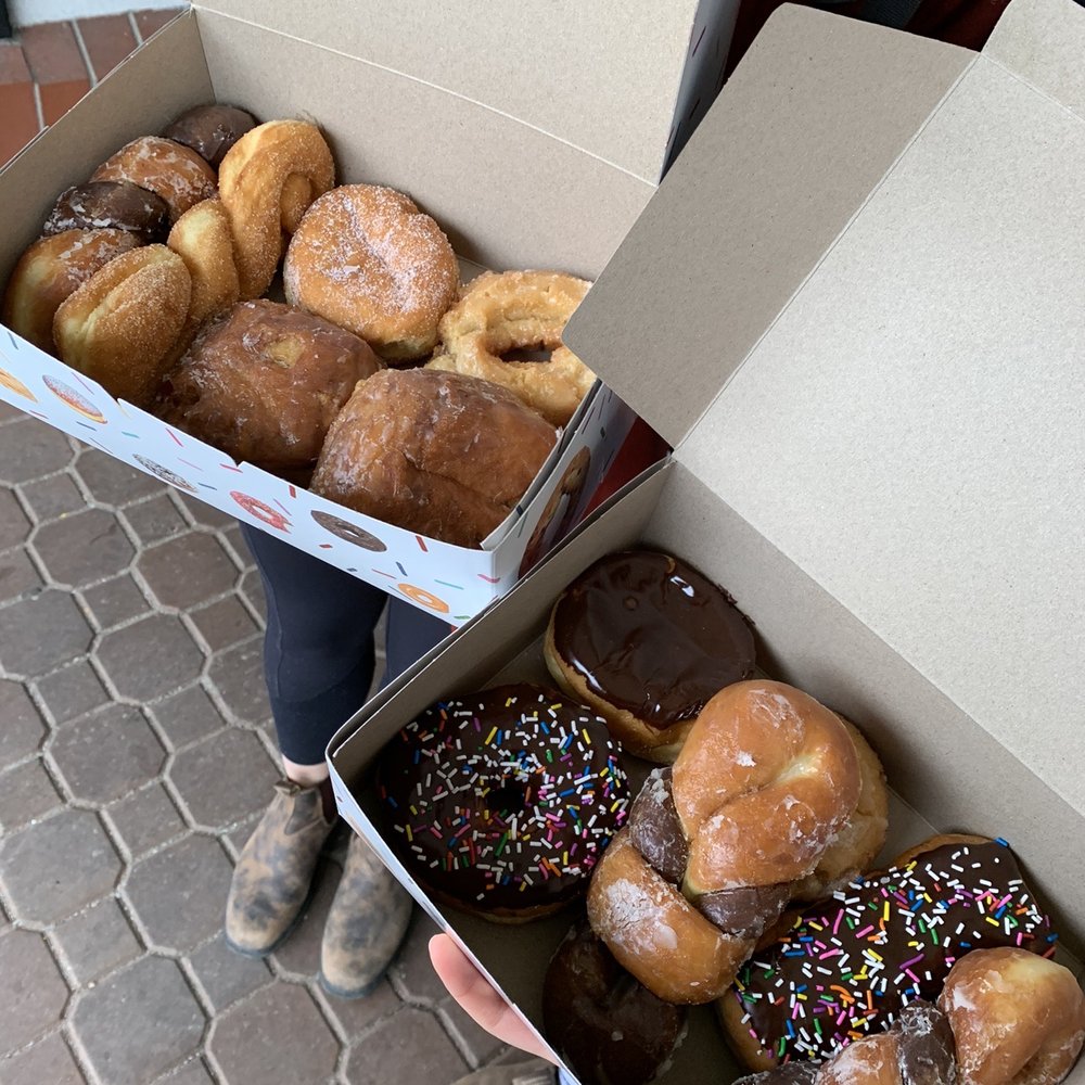 a person holding a box of donuts