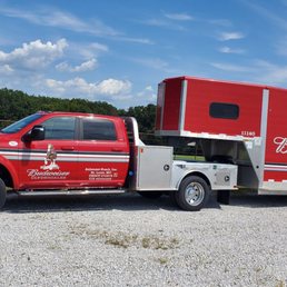 A Bud Ranch truck with a horse trailer in the parking lot. All their equipment is in pristine condition.