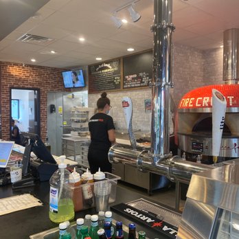 Fire Crust - a man preparing food in a restaurant - Pizza Near Me - Henrietta, New York