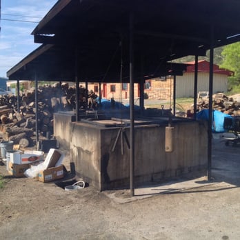 Lum's - The pit, in which my brisket slow cooked all night before.  With a stack of mesquite piled up behind it. - Barbeque Near Me - Junction, Texas