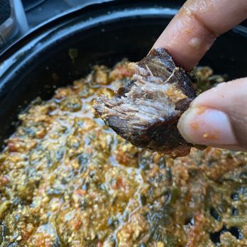 Queensway Restaurant & Catering - a person dipping a piece of meat into a skillet - African Near Me - Riverdale, Maryland