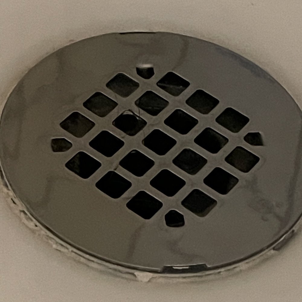 Shower drain installed above shower basin.