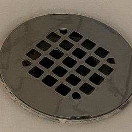 Shower drain installed above shower basin.