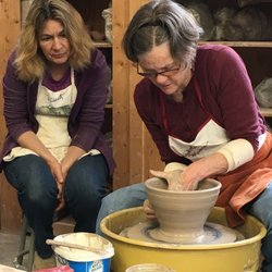 Bay School Community Arts Center - A student looks on while instructor Elizabeth Krome demonstrates throwing techniques.