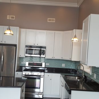 Long Lasting Painting - a kitchen with white cabinets and black countertops - Flooring Near Me Long Lasting Painting - a kitchen with white cabinets and black countertops - Flooring Near Me