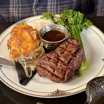 Caroline's Table - Surf and Turf - A dish featuring a grilled steak, mashed potatoes, broccoli, and a baked potato with gravy, served on a decorative plate. - New American Near Me - Denton, Maryland