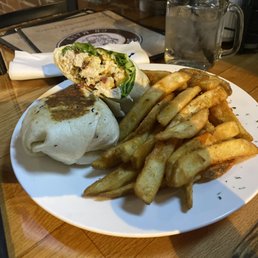 Chicken Bacon Ranch Wrap - A plate with French fries, a burrito, and a wrap, accompanied by a glass of water, on a wooden table at a restaurant.