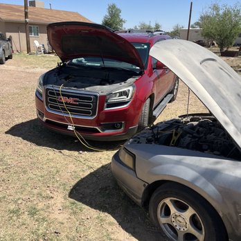 Anthony Locksmith - Car needing to be hooked up to another vehicle due to depleted battery. - A red GMC SUV and a silver car are parked outdoors with their hoods open, connected by jumper cables, indicating a battery jump-start situation. - Keys & Locksmiths Near Me - Canutillo, Texas