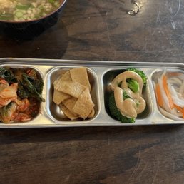 Four dishes. Kimchee, radish, broccoli, fish cake. Four dishes. Kimchee, radish, broccoli, fish cake.