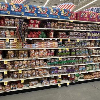 Vons - The image shows grocery store shelves stocked with a wide selection of bread and sandwich buns, including white, whole wheat, and specialty options. Price tags are visible on the shelves, and the background features patriotic-themed umbrellas hanging from the ceiling. The store appears well-organized and brightly lit. - Grocery Near Me - Camarillo, California