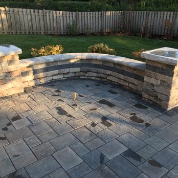 A Garden Guy - a patio with a stone bench - Landscaping Near Me