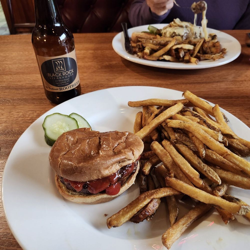 Black Rock Steakhouse - My meal, which i turned to make it less obvious I had taken a bite.  My sister's smothered burger in the background. - Steakhouses Near Me - Springfield, Vermont