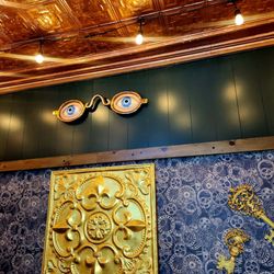 Sophisticated interior details featuring vintage-inspired ocular wall decor, dark green wood paneling, and ornate gold accents.