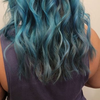 Pascal Pour Elle - A person with long, curly hair dyed in shades of blue and green, viewed from behind, wearing a purple top and patterned pants. - Hair Salons Near Me - Glencoe, Illinois