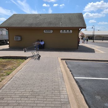 Austin Steam Train Association - People sitting in the shade at the Burnet train Depot waiting to reboard the train at 1:15pm - Trains Near Me - Cedar Park, Texas