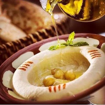 Al-Amir - a bowl of hummus and olive oil being drizzled over a bowl of hummus - Lebanese Near Me - Arlington, Texas Al-Amir - a bowl of hummus and olive oil being drizzled over a bowl of hummus - Lebanese Near Me - Arlington, Texas