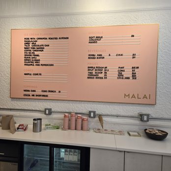 Malai - A pink menu board at Malai in Brooklyn lists ice cream flavors, specials, beverages, and prices, mounted on a textured white wall. - Ice Cream & Frozen Yogurt Near Me - Brooklyn, New York
