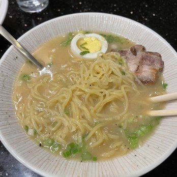 Miso - Disappointing Miso Ramen - A bowl of ramen featuring noodles, a boiled egg, chopped green onions, and a slice of pork, served on a black table. - Japanese Near Me - Round Rock, Texas