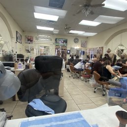 Inside - A nail salon interior with clients seated in pedicure chairs and receiving nail services, with salon equipment and decor visible.