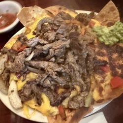 Panchos Mazatlán fried tortillas with beans loaded with fajitas grilled onions green belll peppers and cheese