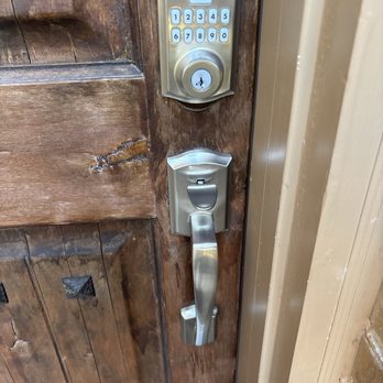 Keep Calm Locksmith - A metallic keypad lock with a handle is installed on a wooden door, used for secure access. The keypad has numbered buttons and a keyhole. - Keys & Locksmiths Near Me - Plano, Texas