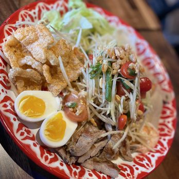Laughing Monk Cafe - Allston - papaya salad with mu yo (pressed pork sausage), deep-fried pork rinds, pickled bamboo shoots, culantro, and boiled eggs - Thai Near Me - Boston, Massachusetts