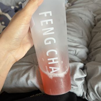 ODD Tea & More - Had to leave Odd Tea, because of my experience went to Feng Cha - Strawberry Overload | no sugar also - A person holds a frosted plastic cup containing red beverage with foam, with the text "FENG CH" printed on it, against a background of gray clothing. - Bubble Tea Near Me - Tomball, Texas