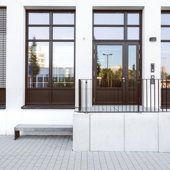Builders FirstSource - Tall, multi-pane windows next to a glass entry door on a modern white building exterior, emphasizing clean lines and vertical... - Building Supplies Near Me - Mitchell, South Dakota Builders FirstSource - Tall, multi-pane windows next to a glass entry door on a modern white building exterior, emphasizing clean lines and vertical... - Building Supplies Near Me - Mitchell, South Dakota
