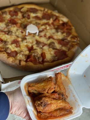 Photo of Falcone's Pizza - Pico Rivera, CA, US. a hand holding a box of wings and a pizza