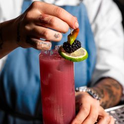 ORA FreeStyle Italian - Close up image of red cocktail being garnished by a bartender with tattoos.