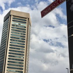 Visit Baltimore - The World Trade Center in the background of the Iconic "Charm'tastic Mile" Street Sign.